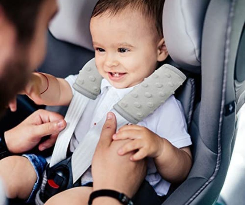 man clipping baby into car seat with great car strap covers
