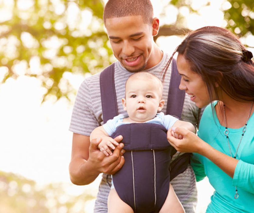 couple holding baby in front facing baby carrier