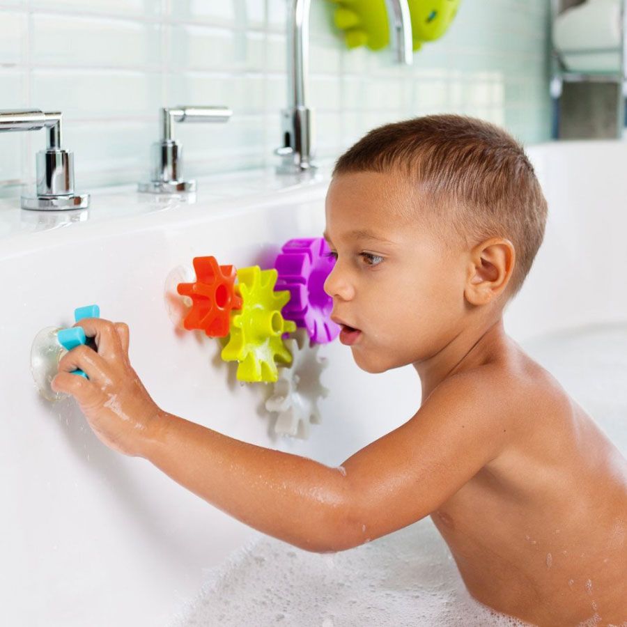 Child in tub playing with colorful the Boon Cogs Water Gear Bath Toys
