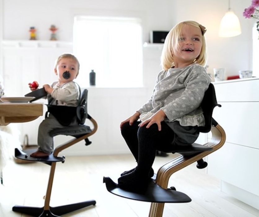 baby and toddler each sitting in a black nomi high chair