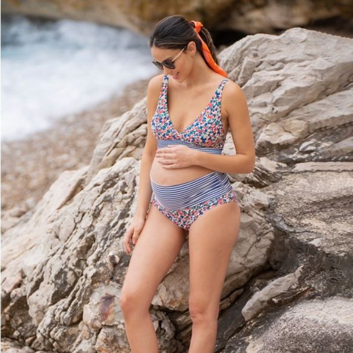 pregnant woman wearing a materntiy bikini next to a rock