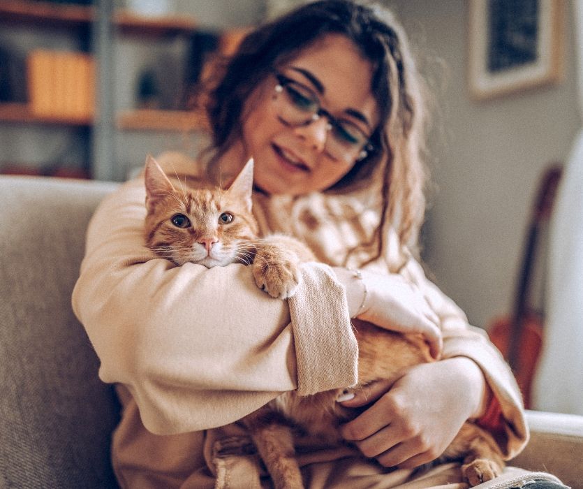 woman holding her pet cat on a couch