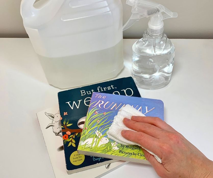 bottle of vinegar and spray bottle next to hand cleaning board books
