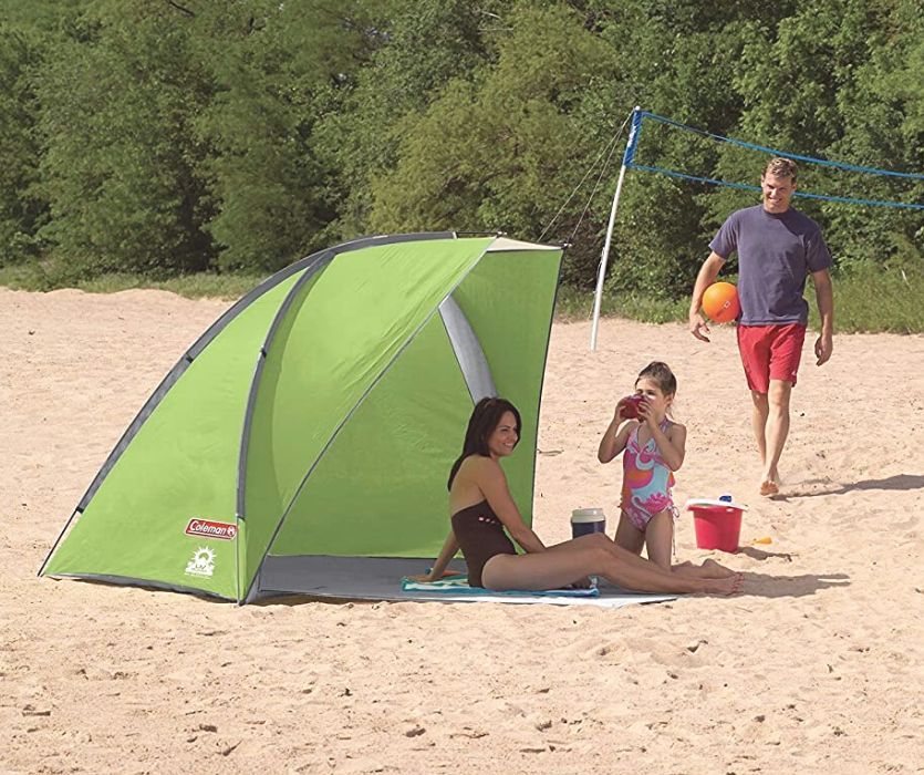 family sitting in green beach tent