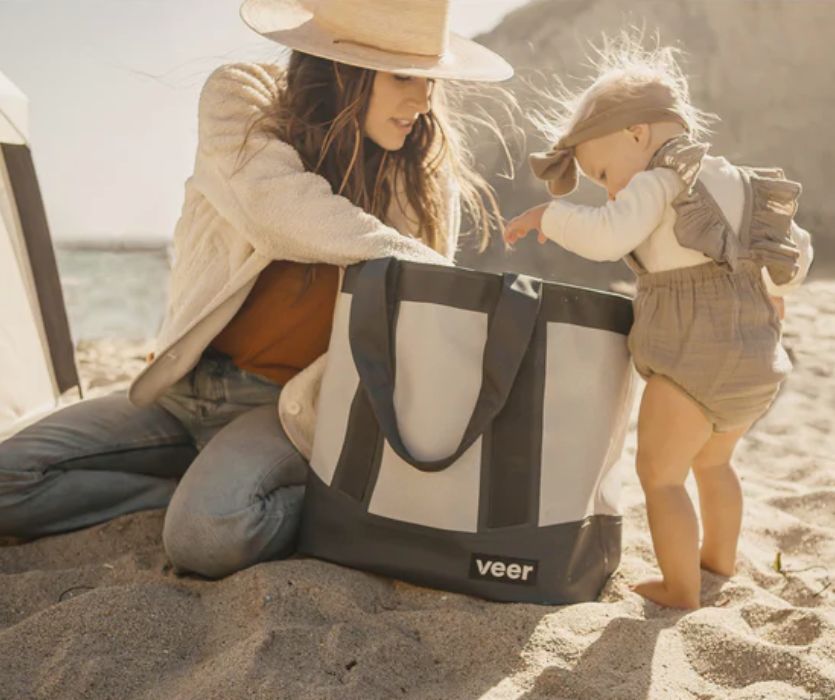 mom and toddler on the beach with a veer beach bag