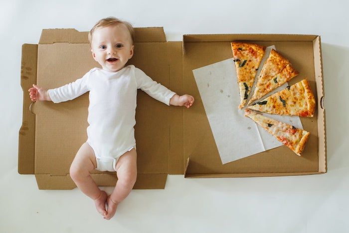 baby shown with a box of pizza representing 4 months