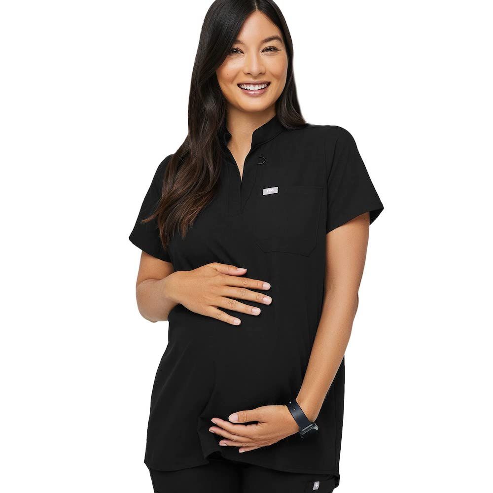 pregnant woman holding her bump in short sleeved black scrubs
