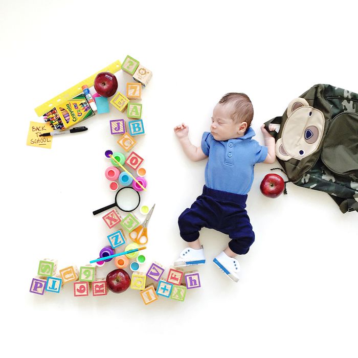 number 1 spelled out with school supplies next to one month old baby