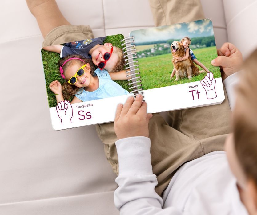 child holding custom photo board book with images and sign language illustrations