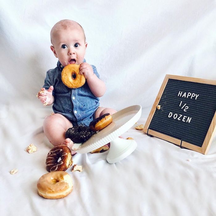 baby eating donuts next to happy half dozen sign