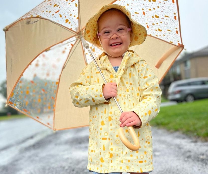 child wearing a yellow raincoat and umbrella