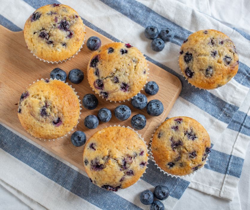 blueberry muffins on board with blue and white striped towel