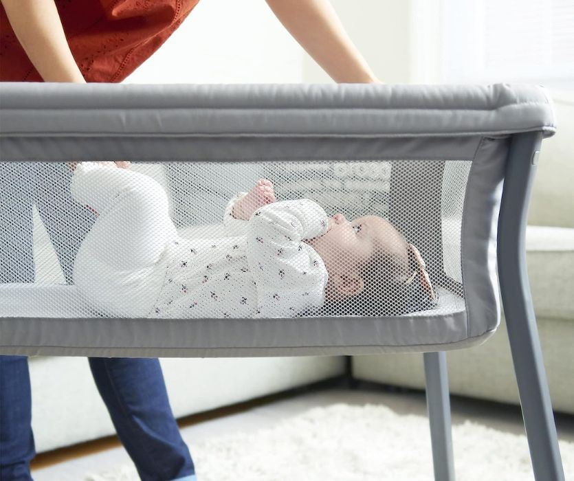 baby in a grey portable crib
