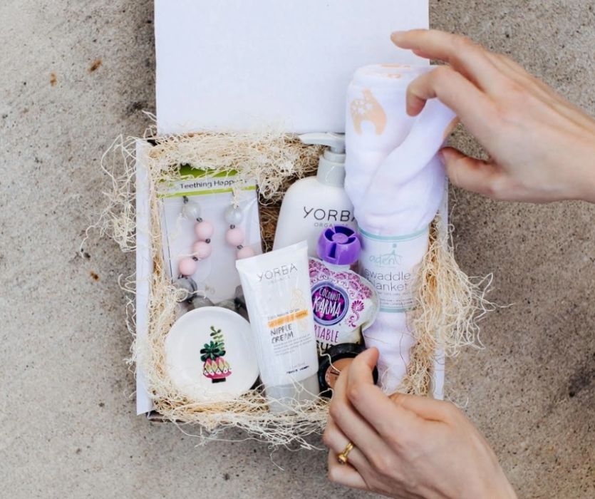 Mama Bird Box pregnancy subscription box showing selection of goods - creams, a swaddle, teething beads and other trinkets. 