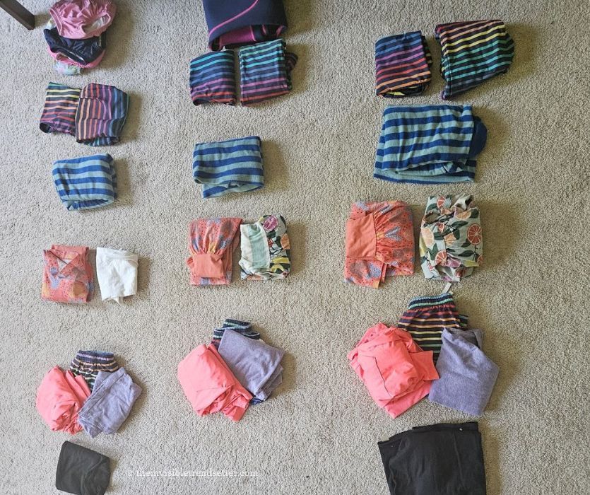 Rows of kid clothes laid out on a beige carpet.