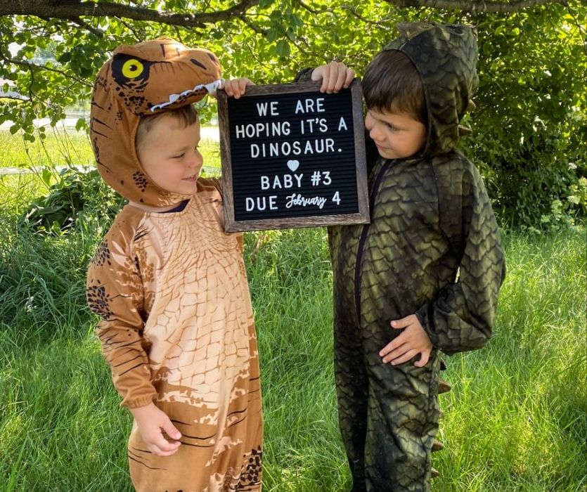 siblings dressed as dinosaurs expressing their baby brother.