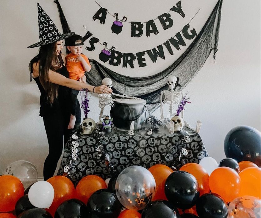 mom and toddler in front of baby brewing halloween announcement