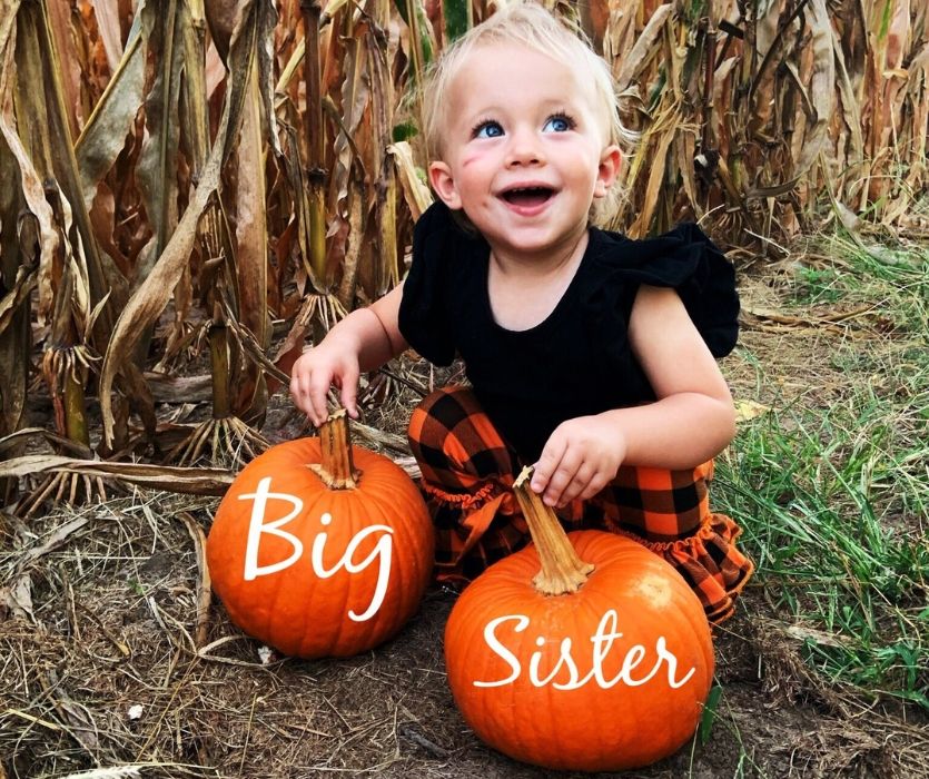 toddler with big sister written on pumpkins