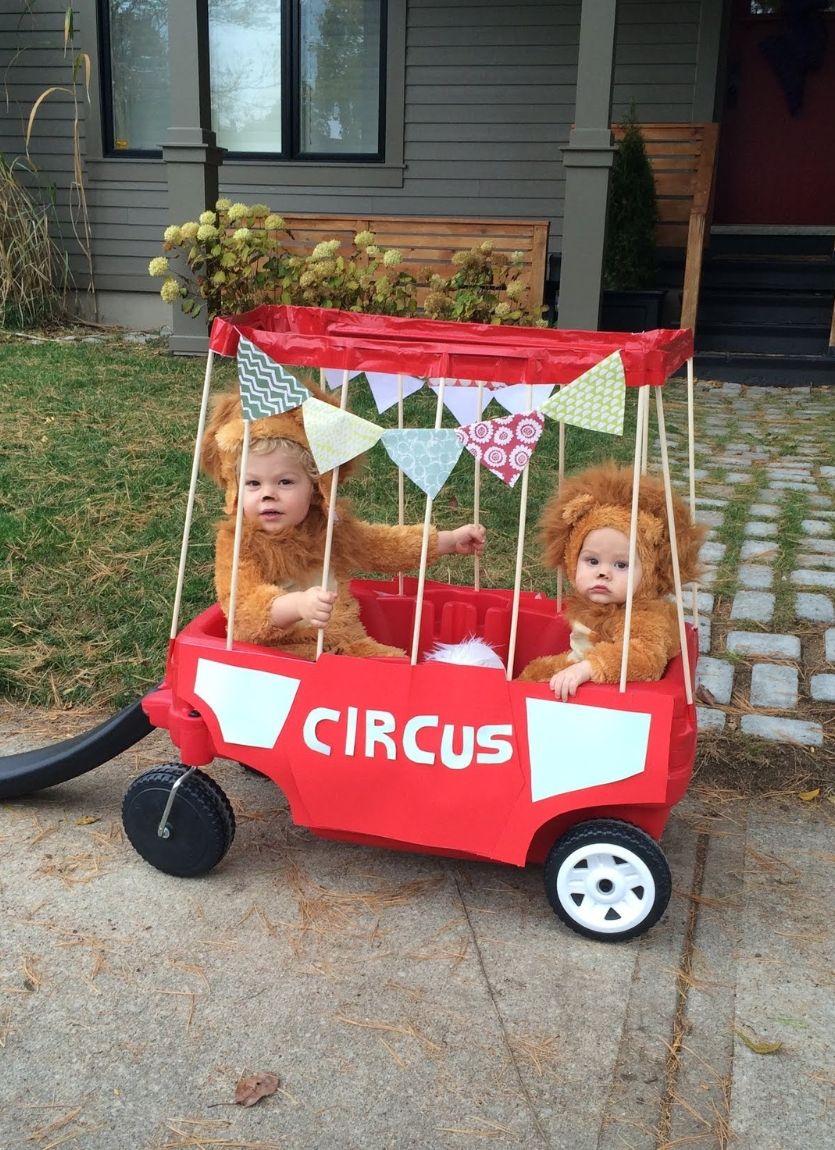 two babies dressed as lions sitting on a circus train wagon
