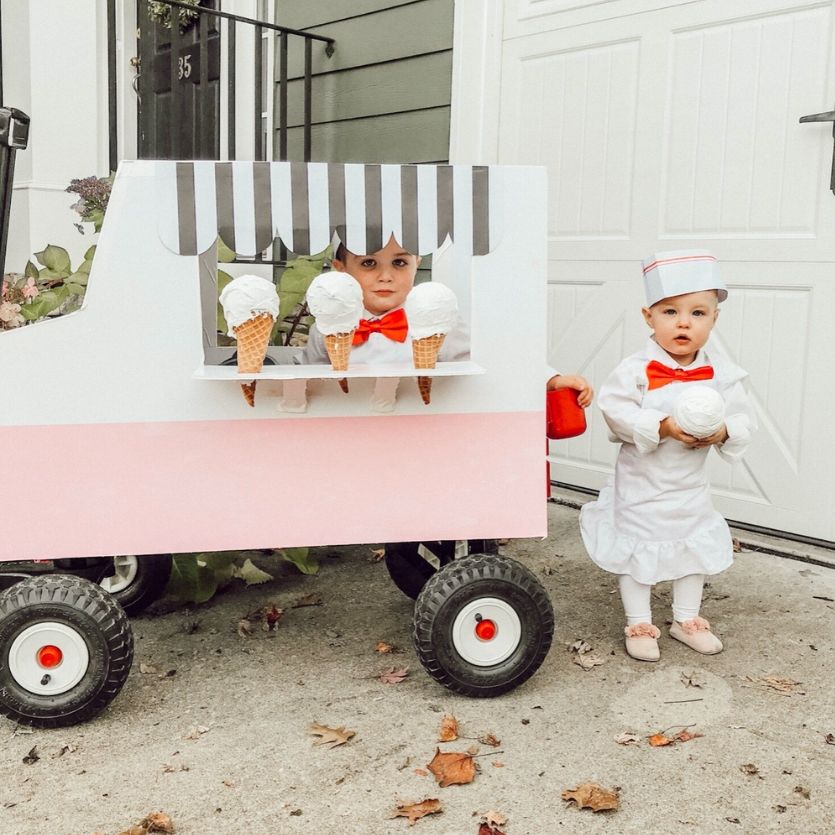 two toddlers beside a wagon made to look like an ice cream truck