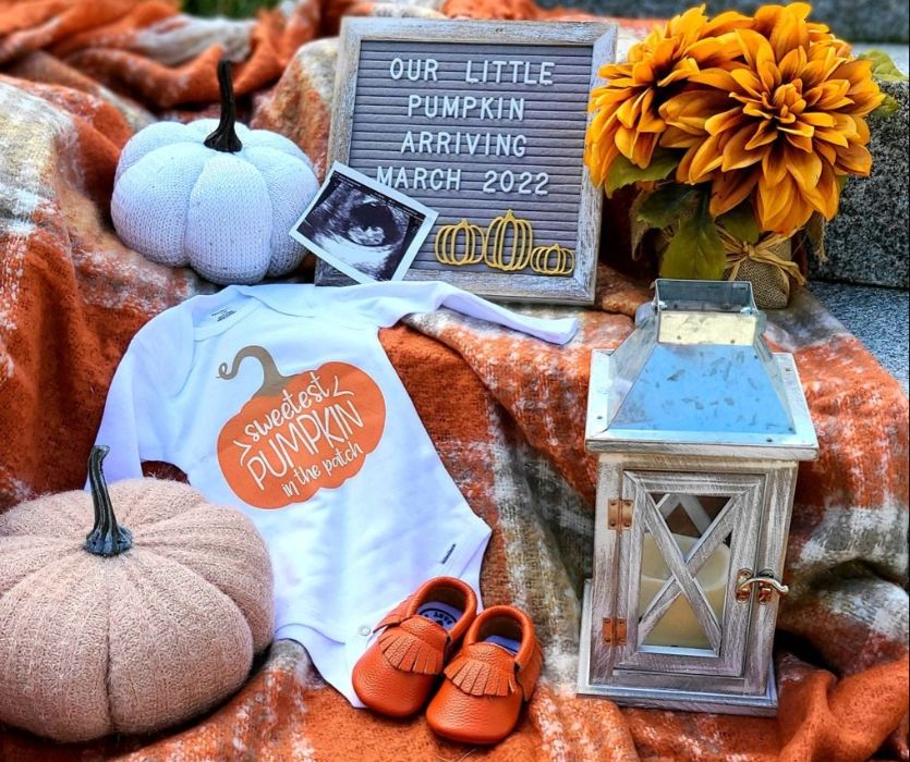 fall decor announcing a pregnancy on letterboard with pumpkin onesie