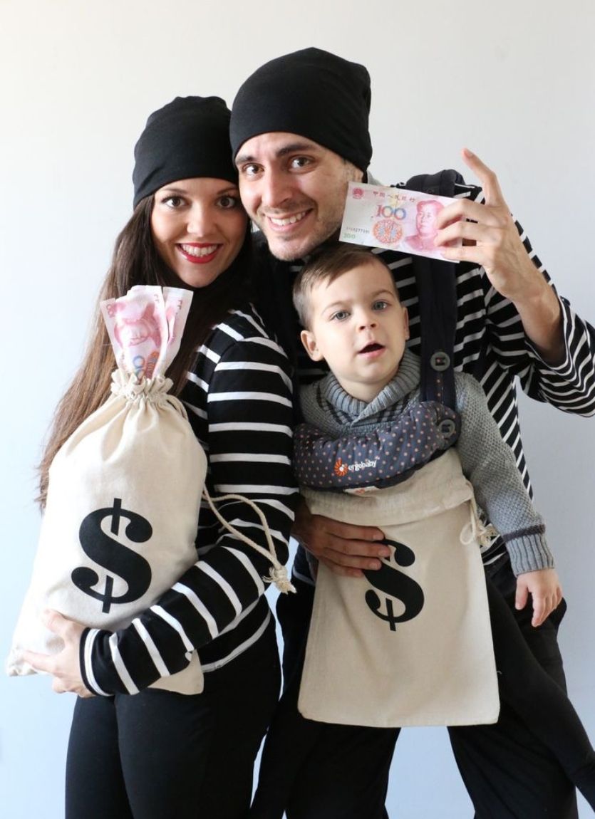 mom and dad dressed as bank robbers with a toddler wearing a money bag