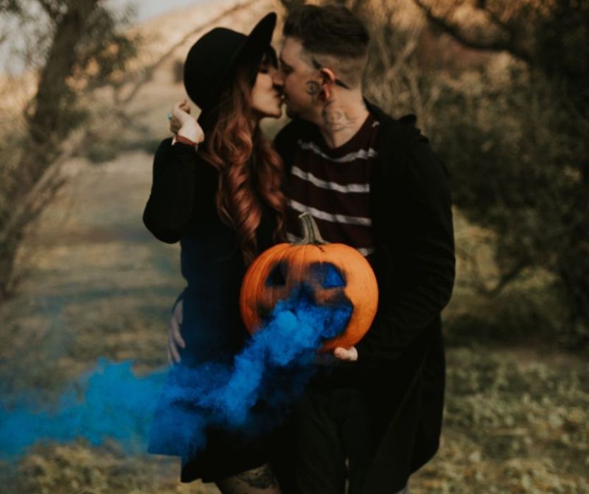 couple kissing with carved pumpkin halloween gender reveal