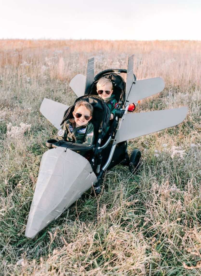 two kids sitting in a stroller made to look like a Super Hornet
