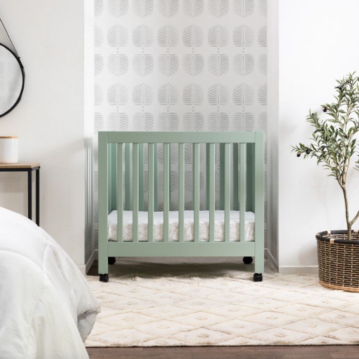 green mini crib in master bedroom