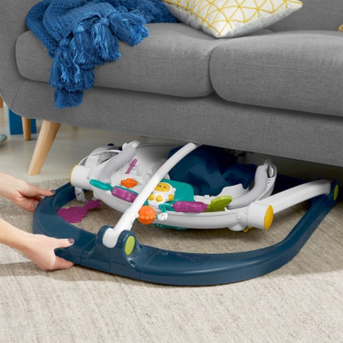 infant activity center folded being pushed under a couch