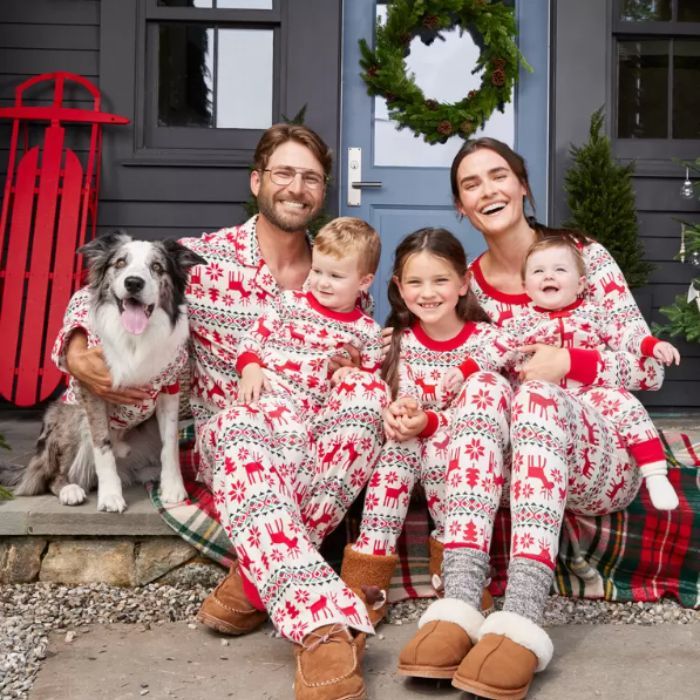 family sitting on porch wearing holiday pajamas with their pet dog