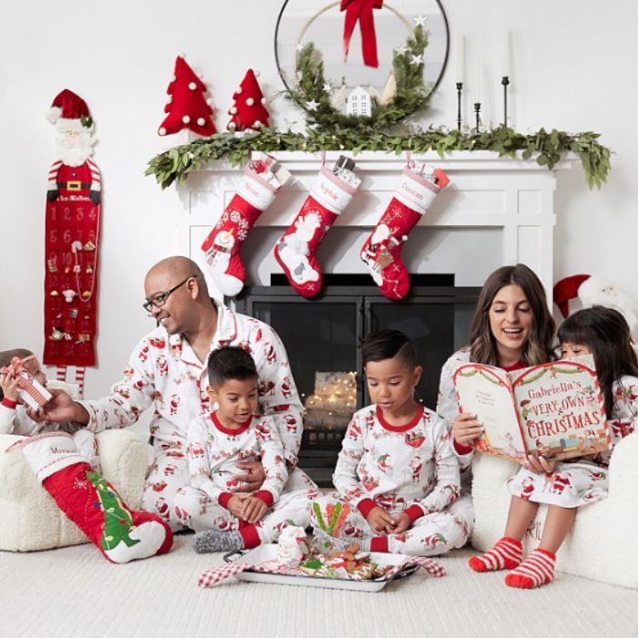 family sitting in livingroom christmas morning wearing holiday pajamas