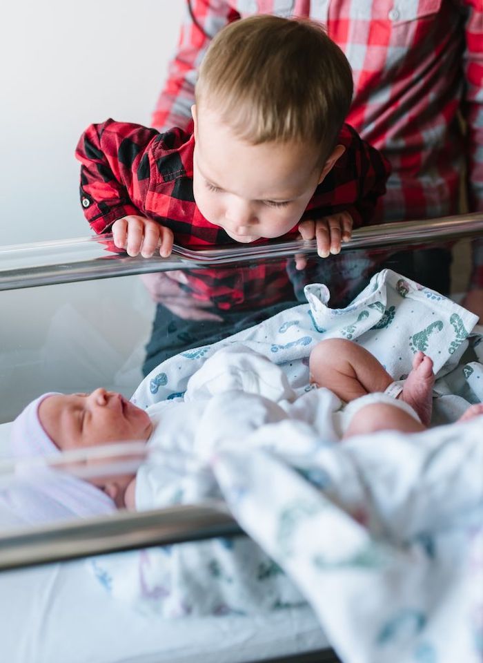 Toddler big brother leaning over newborn baby fresh 48 hospital photo