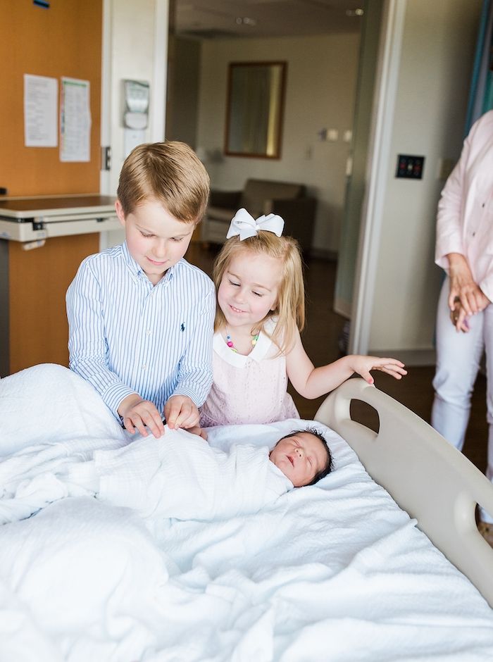 Older boy and girl siblings meeting newborn baby at hospital