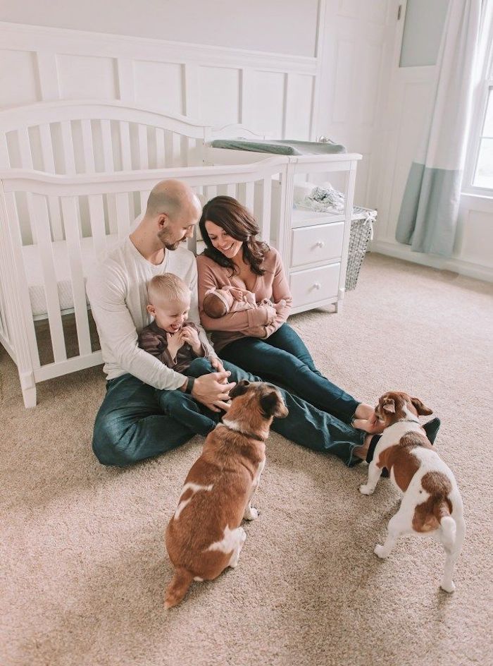 Family posing in nursery with son newborn baby and two dogs