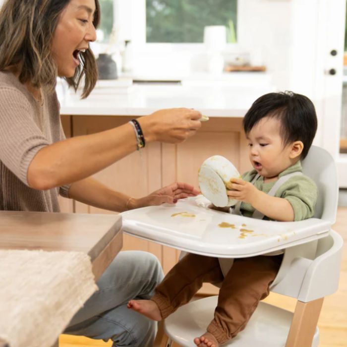 mom feeding her child off the tray of the mockingbird high chair