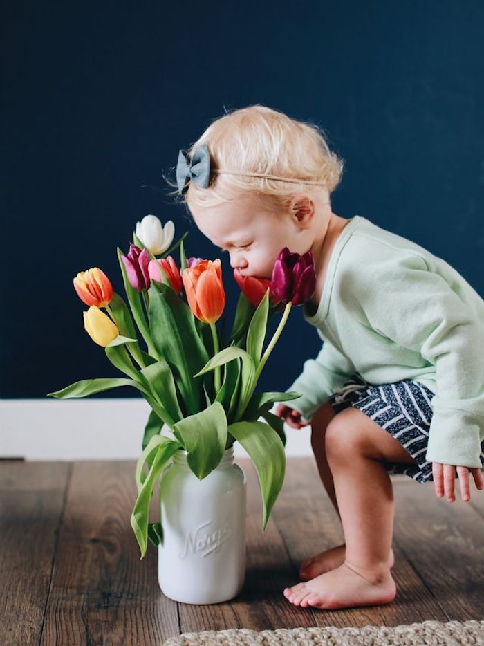 Baby's first Easter spring photo smelling fresh tulips in vase