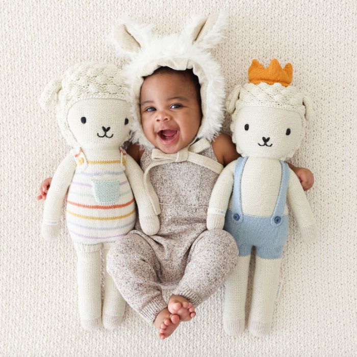 baby with bunny ear holding two stuffed animals