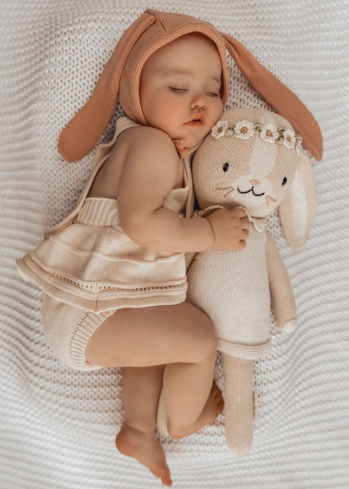 baby wearing bunny ears sleeping next to hannah the bunny
