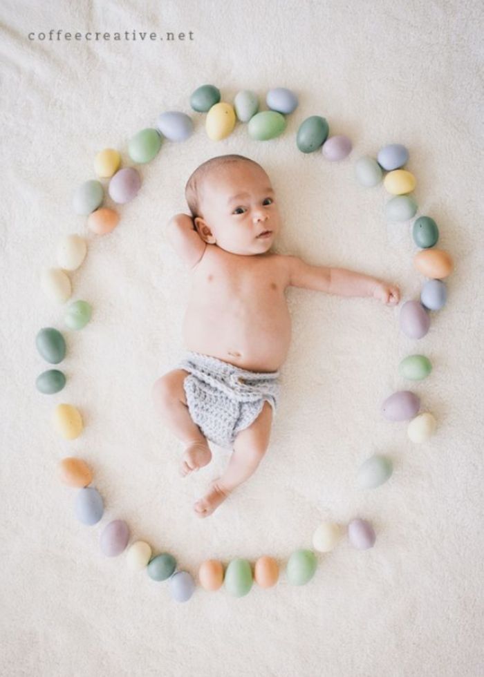 newborn baby surrounded by pastel easter eggs