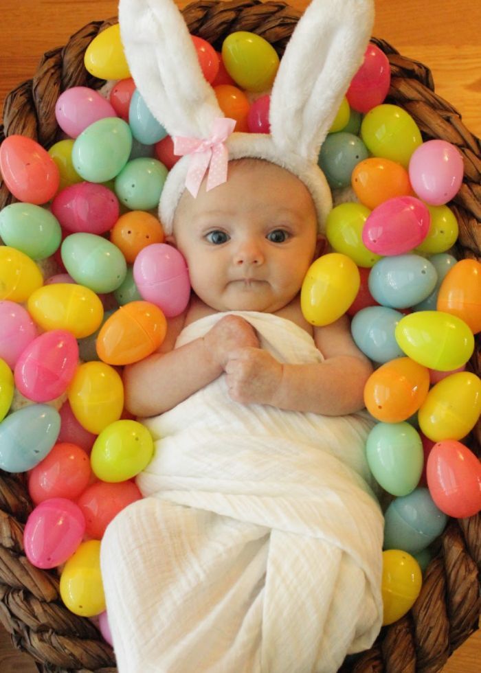 baby in a basket full of plastic easter eggs