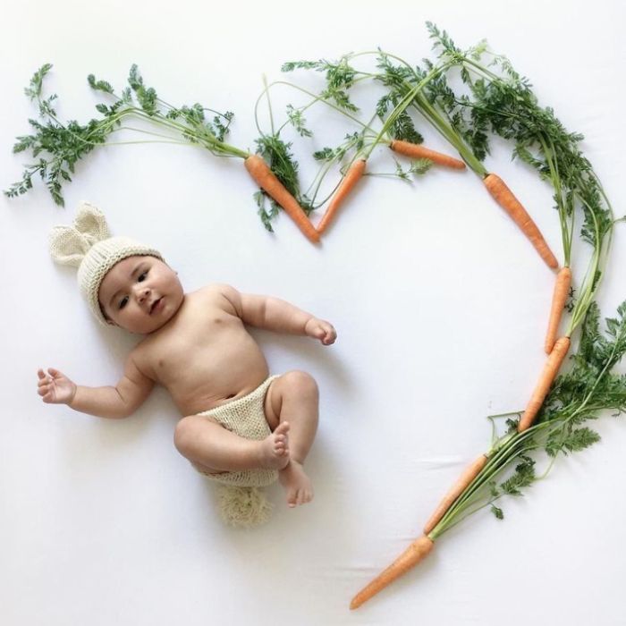 baby wearing bunny hat surrounded by carrots shaped like a heart