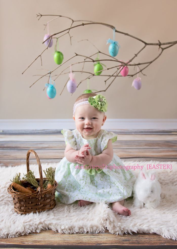 baby in spring outfit with a tree branch with easter eggs on it