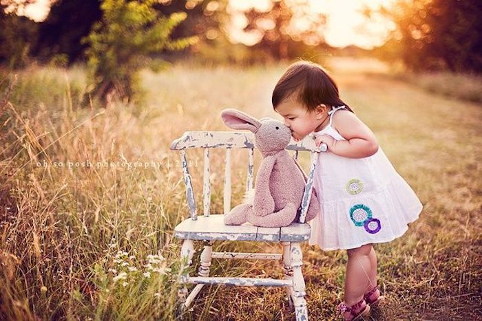 baby's first Easter outdoor photo kissing stuffed bunny toy sitting on chair in field