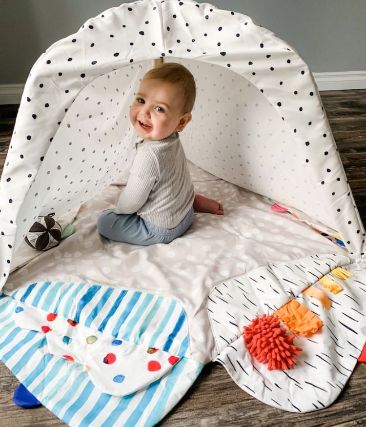 toddler sitting in lovevery play gym mat