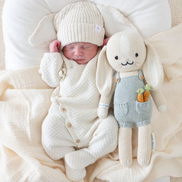 infant dressed in ivory with stuffed rabbit