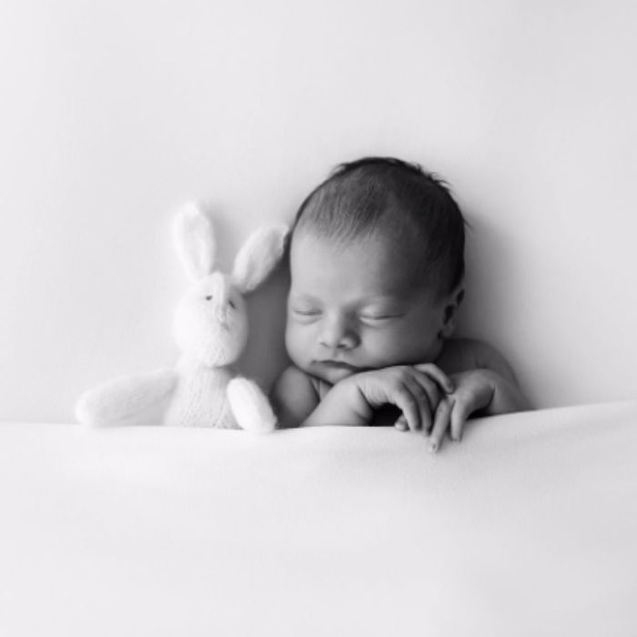 black and white photo of baby with stuffed bunny