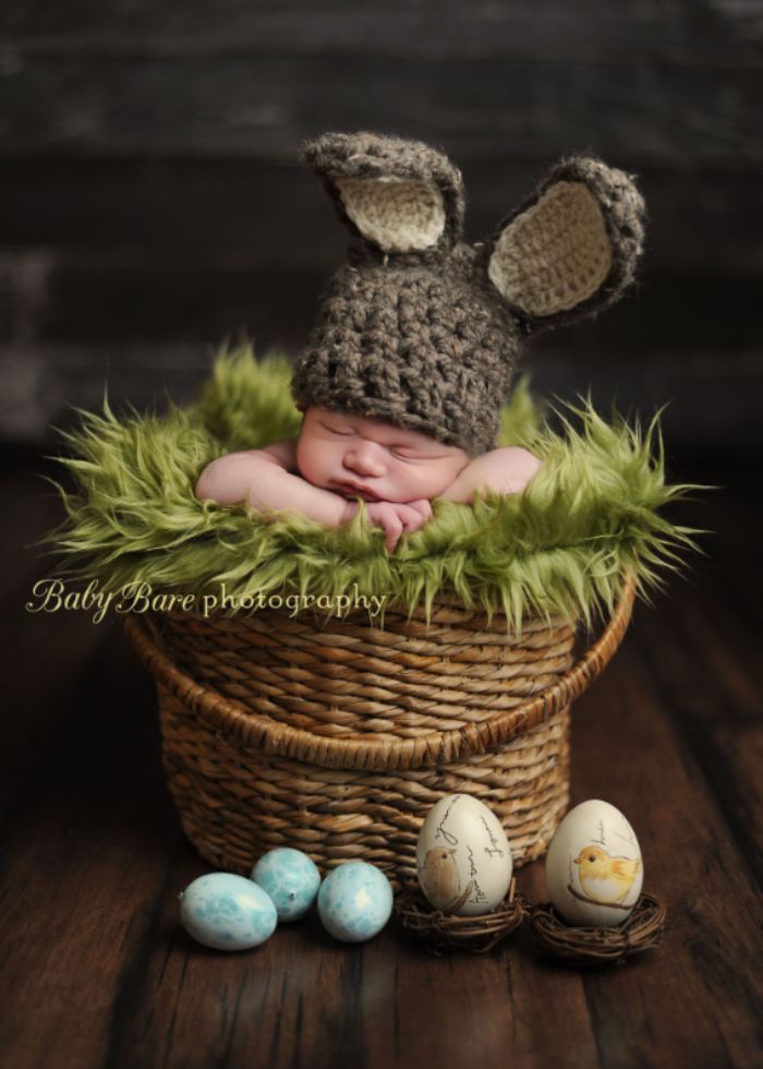 photoshoot of baby wearing bunny ear hat in a basket surrounded by eggs