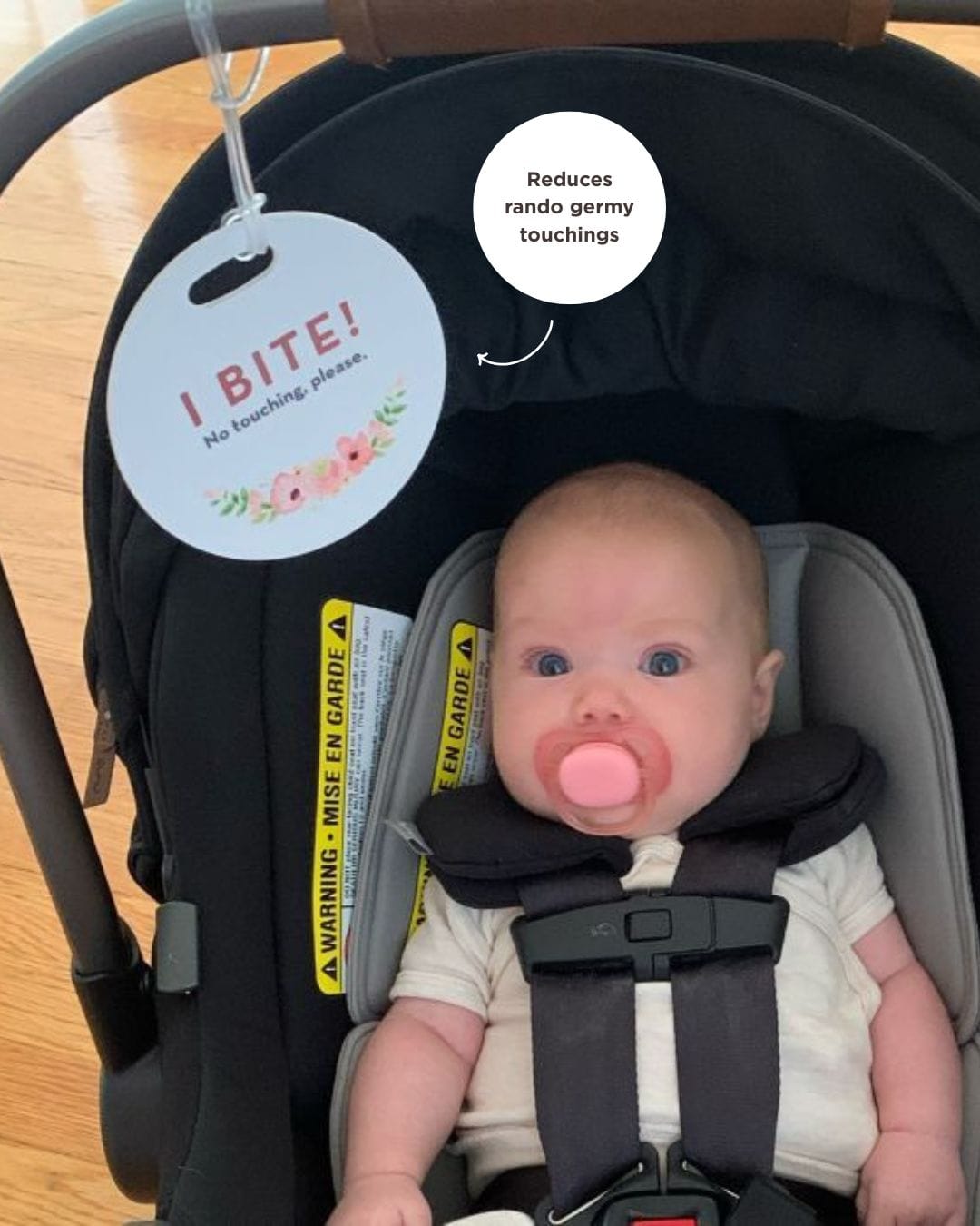 baby in a car seat with a sign to keep stangers from touching her