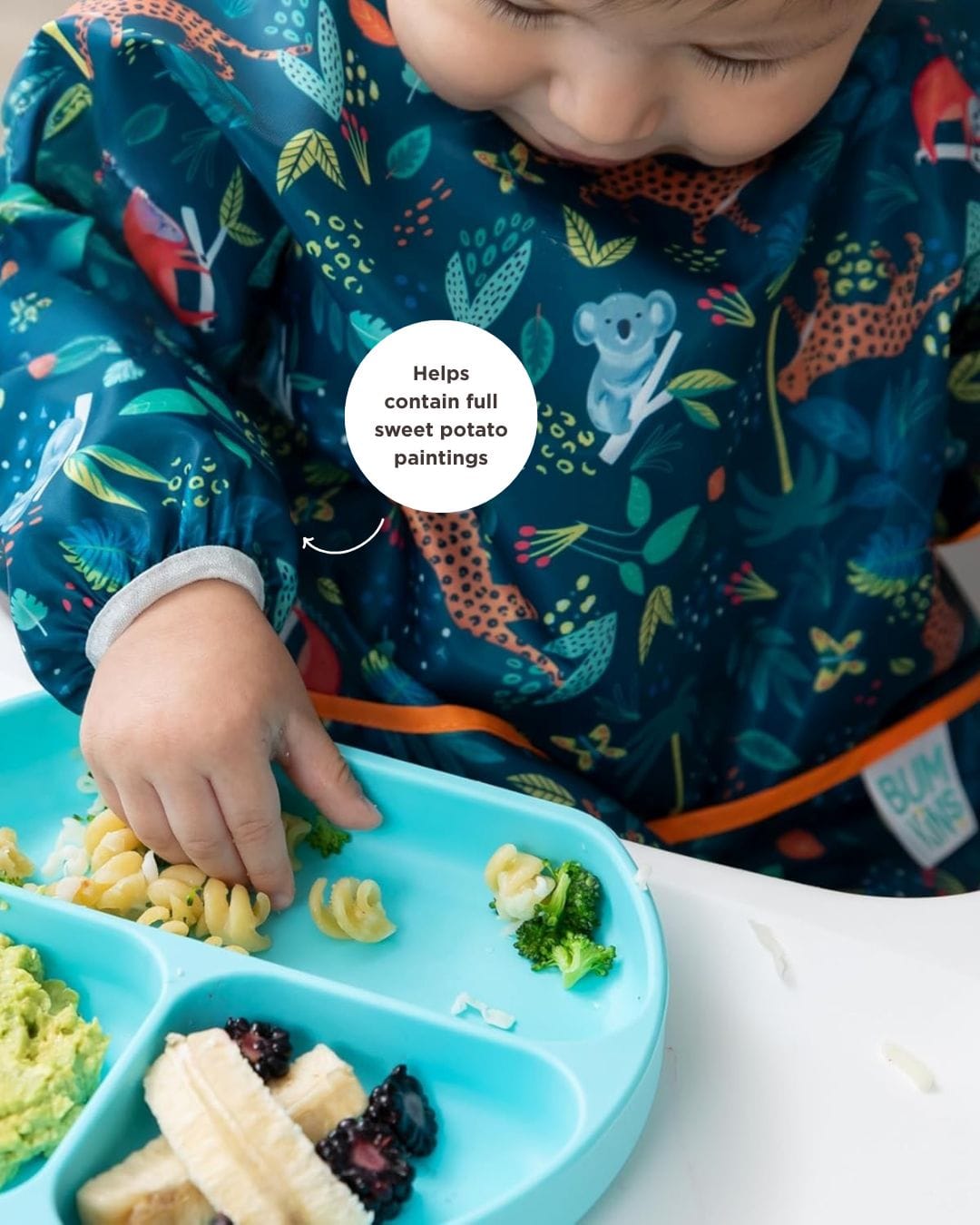 baby with long sleeved bib eating food